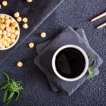 Soy sauce in a bowl and soy beans on the table. Top view