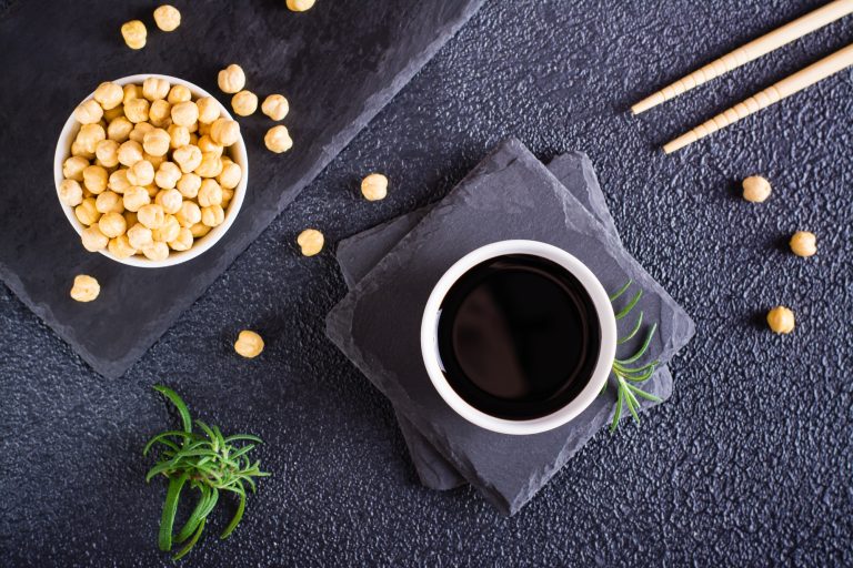 Soy sauce in a bowl and soy beans on the table. Top view